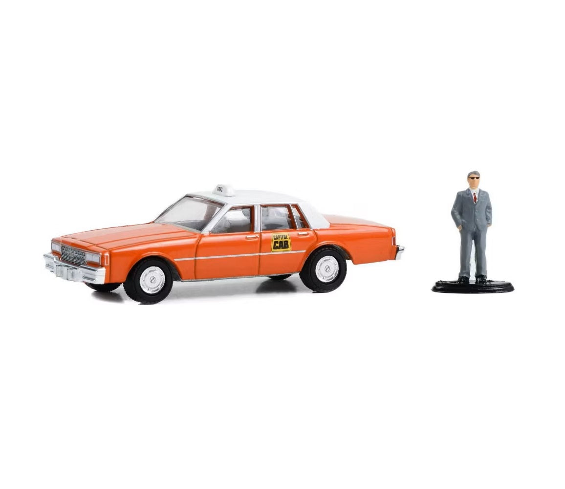 Greenlight - Chevrolet Impala « Capitol Cab » de 1981, taxi orange avec toit blanc et figurine d'homme en costume - Série Hobby Shop - Échelle 1/64